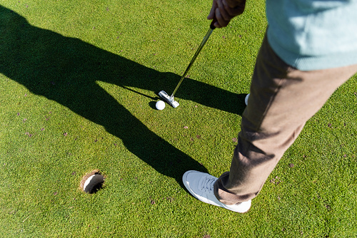 top view of man in white sneakers playing golf on lawn, banner