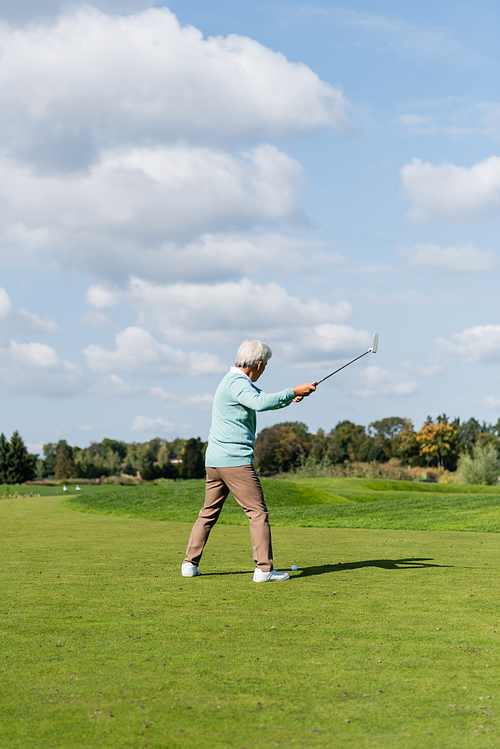 back view of senior asian man playing golf on field