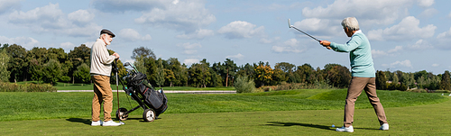 senior asian man playing golf near friend with golf cart, banner