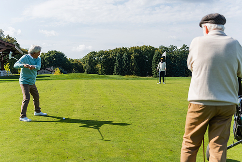 senior asian man playing golf with interracial friends