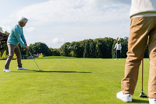 senior asian man playing golf with wealthy interracial friends