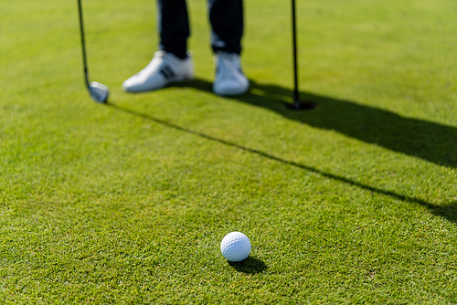 golf ball on green lawn near blurred man