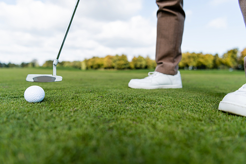 cropped view of blurred man playing golf on lawn