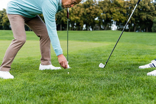 asian senior man putting ball on golf tee