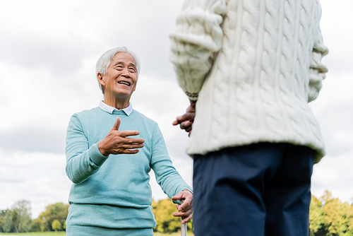 low angle view of happy senior asian man talking with african american friend