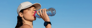 sportive woman in  drinking refreshing water against blue sky, banner