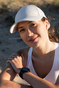 portrait of happy sportswoman in  listening music in wireless earphone on beach