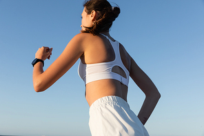 low angle view of young and sportive woman jogging against blue sky in summer