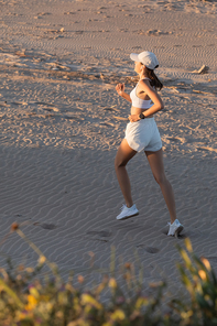 young sportive woman in  and wireless earphone running on sand