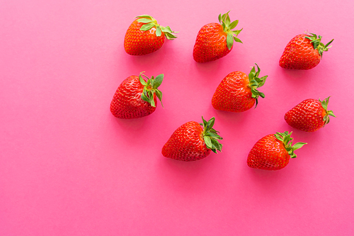 Top view of juicy strawberries on pink background