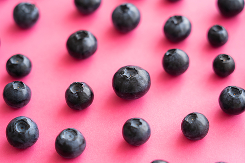 Close up view of fresh blueberries on pink surface