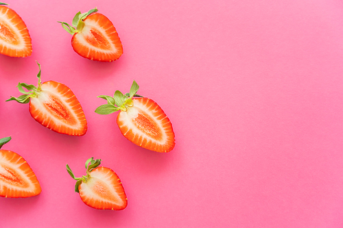 Flat lay of cut fresh strawberries on pink background