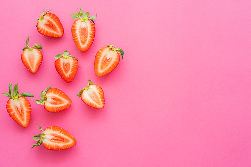 Top view of cut strawberries on pink background with copy space