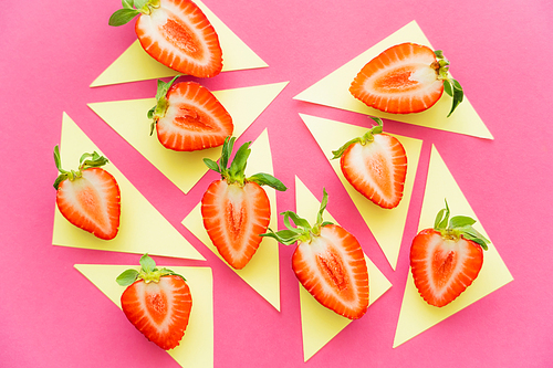 Flat lay of strawberries on yellow triangles on pink background