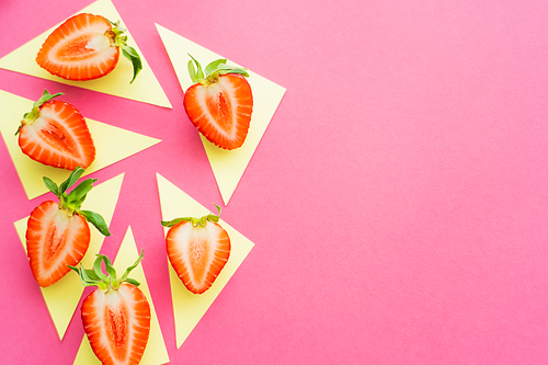 Flat lay with juicy strawberries on yellow triangles on pink background