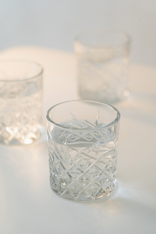 close up view of crystal glass with fresh water on grey blurred background