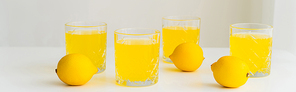 glasses with fresh citrus tonic near whole lemons on white surface and grey background, banner