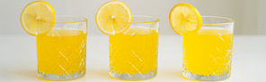 glasses with refreshing lemonade with slices of juicy lemon on white surface isolated on grey, banner