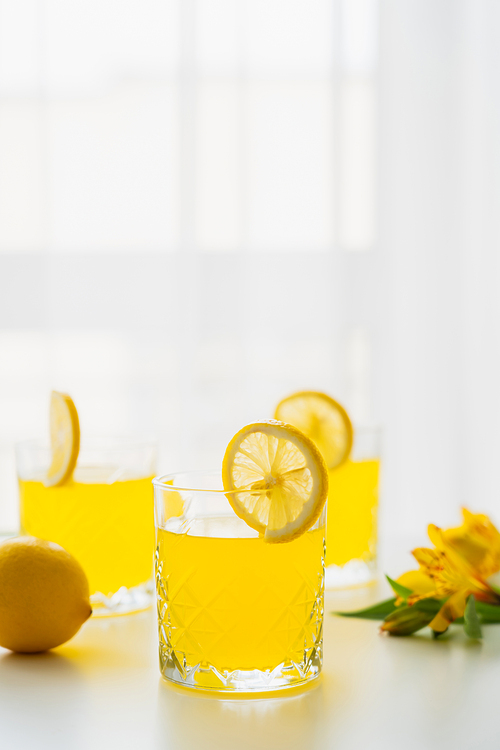 glasses of homemade citrus juice with lemon slices on white background