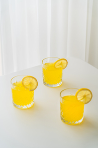 glasses of refreshing lemonade with slices of ripe lemon on white tabletop