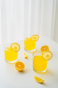 refreshing citrus drink and lemon slices on white tabletop and blurred background