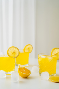 natural citrus tonic and sliced lemons near ice cubes on grey background