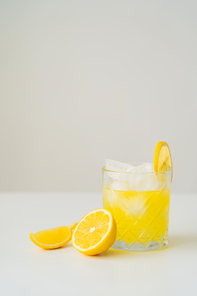citrus tonic with ice cubes near cut lemon on white surface isolated on grey