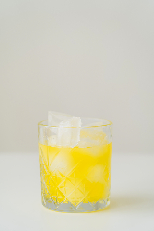 glass with fresh citrus tonic and ice cubes on grey background with copy space