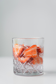 close up view of glass with fresh strawberry tonic on white surface isolated on grey