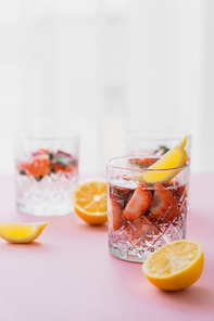 tonic water with lemon and strawberries on blurred background with white copy space