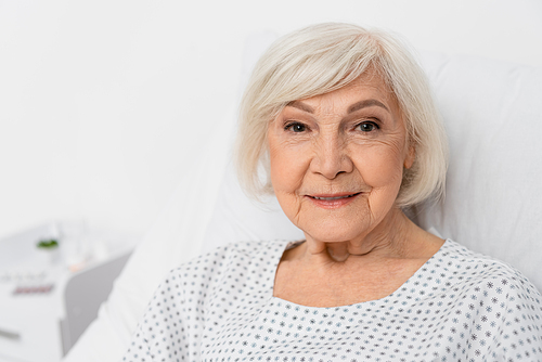 Elderly woman smiling at camera in hospital ward