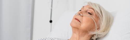 Senior woman with nasal cannula lying on bed in hospital, banner