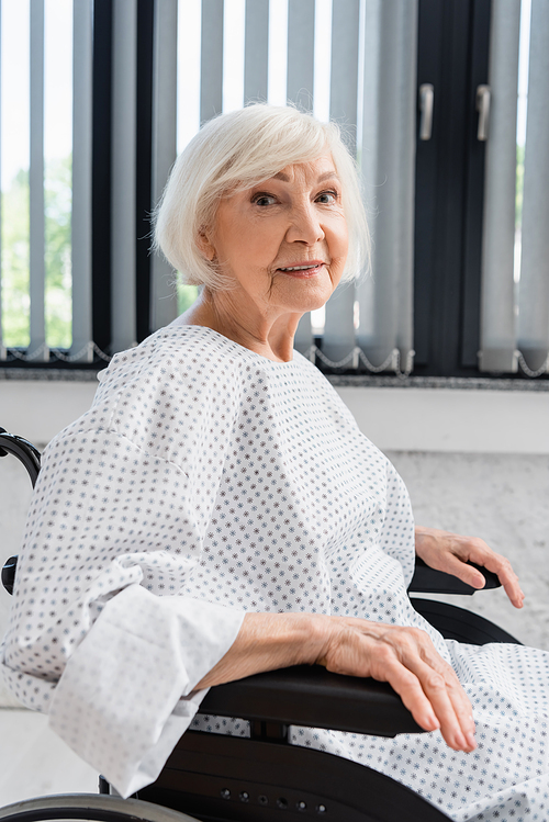 Senior patient smiling while sitting in wheelchair in clinic