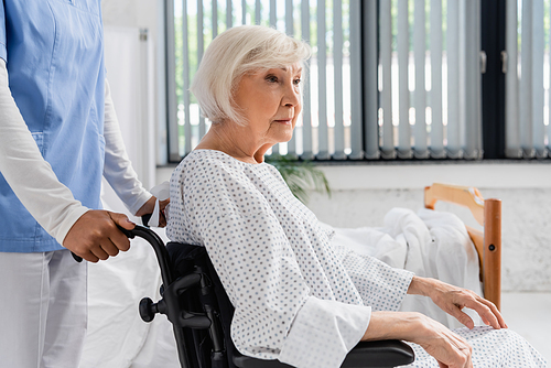 African american nurse standing near wheelchair and patient