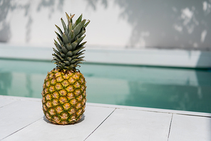 tropical and ripe pineapple near blue water in swimming pool