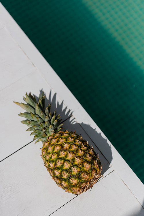 top view of tropical and ripe pineapple near blue water in swimming pool