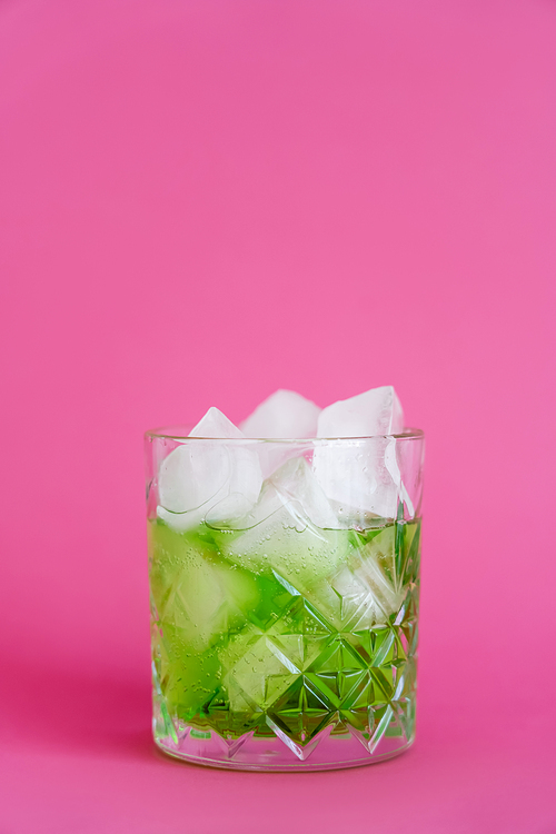 frozen ice cubes in glass with green mojito drink on pink