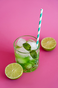 high angle view of frozen ice cubes in glass with mint and green mojito drink on pink