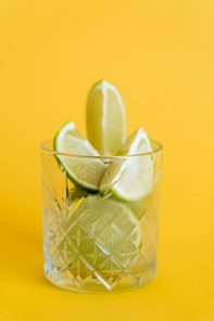 cool faceted glass with sliced fresh limes on yellow