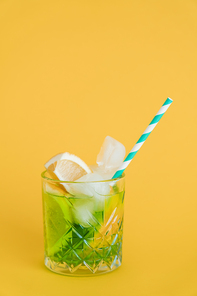 sliced citrus fruit in glass with mojito drink and straw on yellow