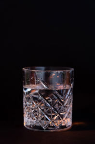 cool faceted glass with rum isolated on black