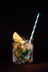 cool faceted glass with mojito and ice cubes isolated on black