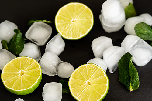 high angle view of melting ice cubes near sliced limes on black background