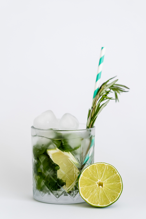 cool faceted glass with mojito, straw and ice cubes isolated on white