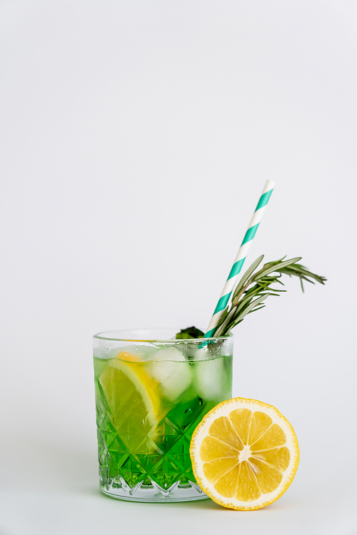 cool faceted glass with lemon mojito, ice cubes and rosemary on white