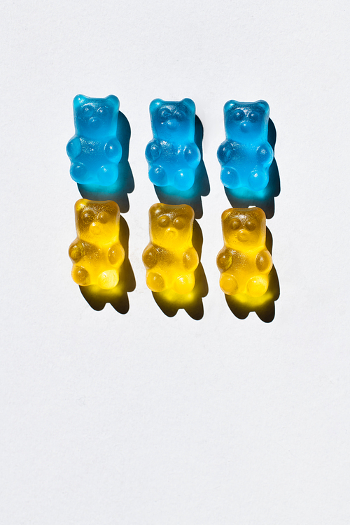 Top view of blue and yellow gummy bears on white background