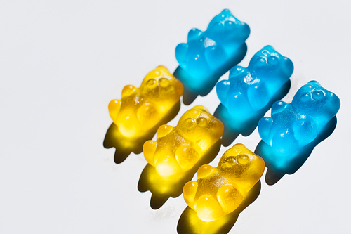 High angle view of yellow and blue gummy bears on white background