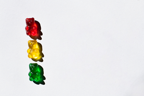 Top view of colorful gummy bears on white background with copy space