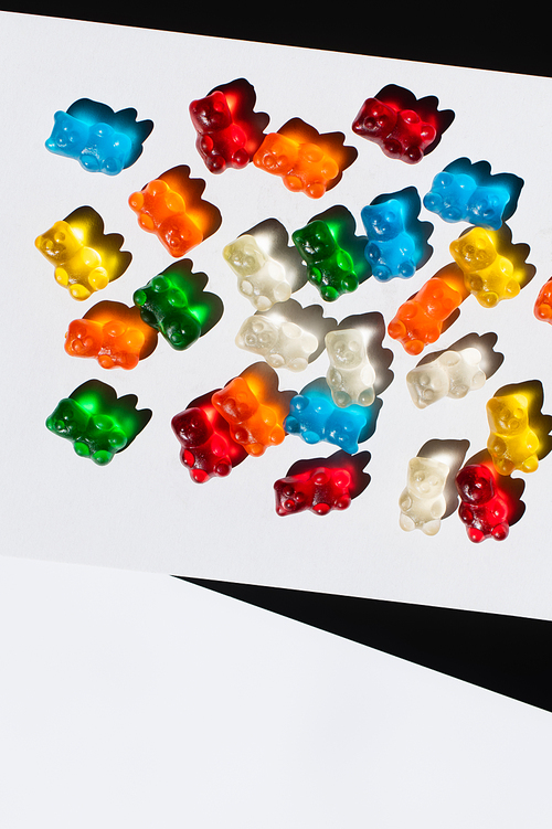 Top view of colorful gummy bears on white and black background