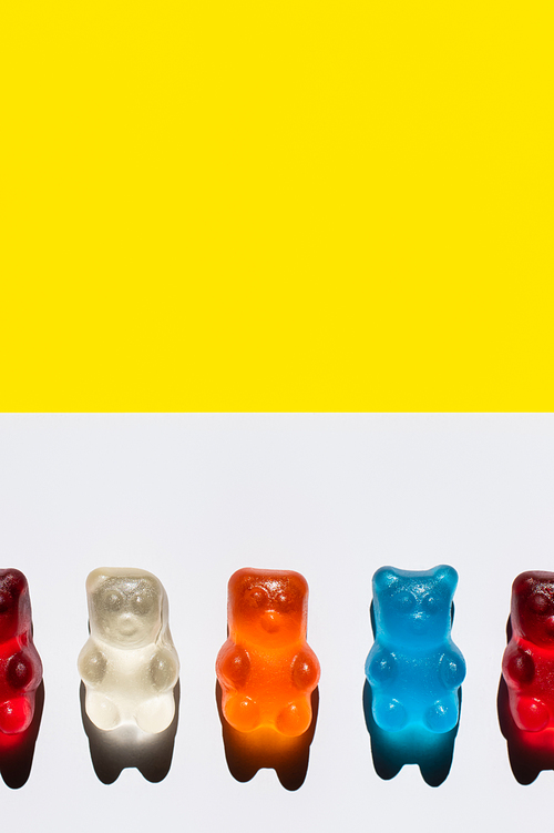 Close up view of colorful jelly bears on white and yellow surface